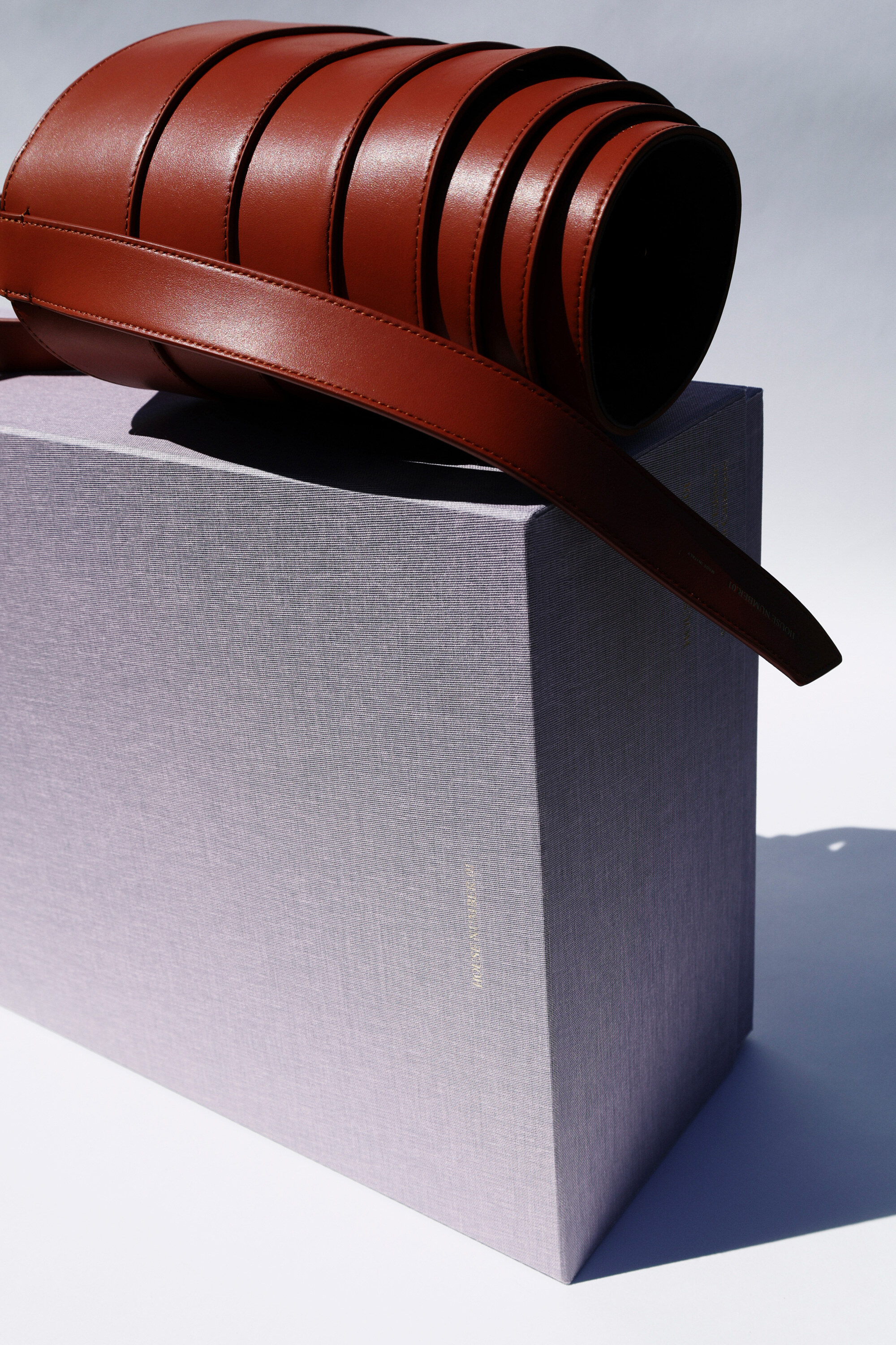 Cognac leather belt on a lavender box