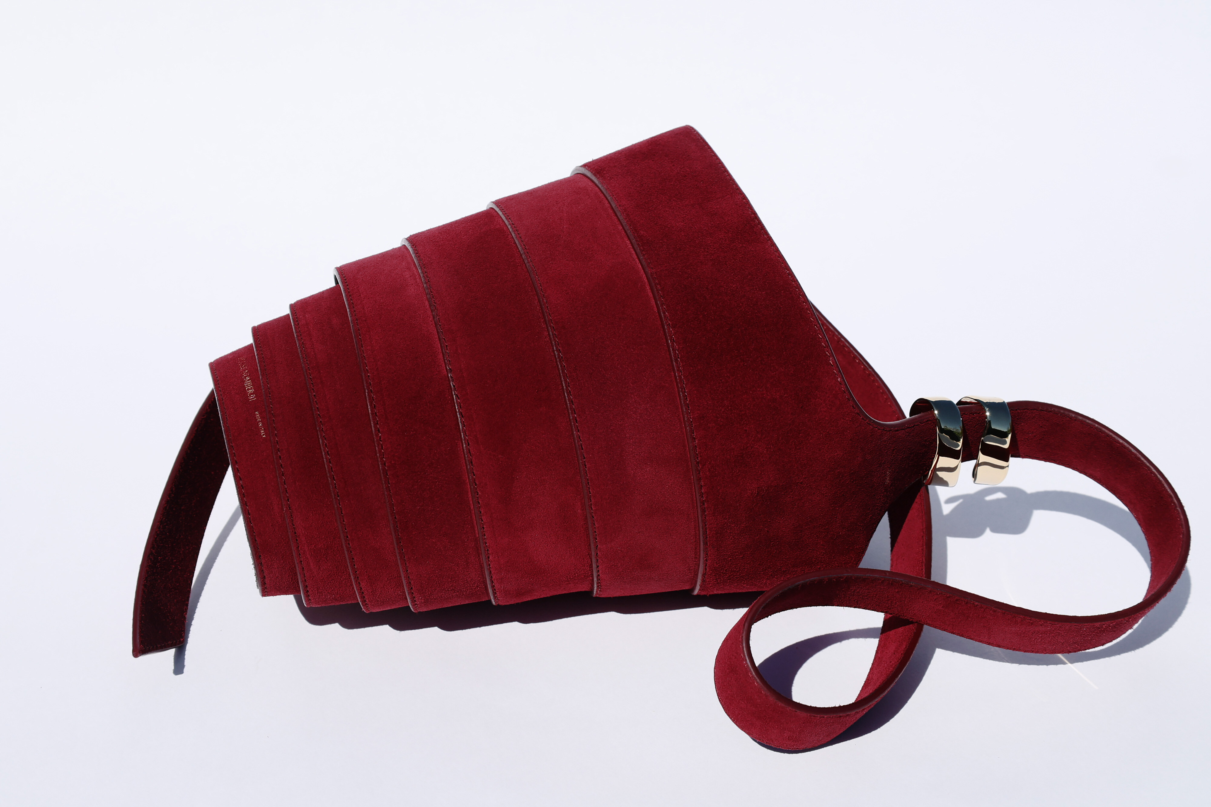 The Spiral Bag in burgundy suede, on its side